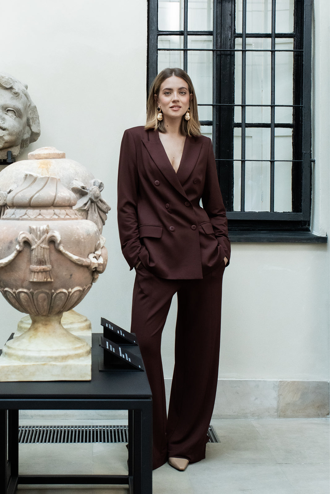 Kobieta w eleganckim, bordowym garniturze z dopasowanym płaszczem i szerokimi spodniami, stylowa moda damska z precyzyjnym krawiectwem