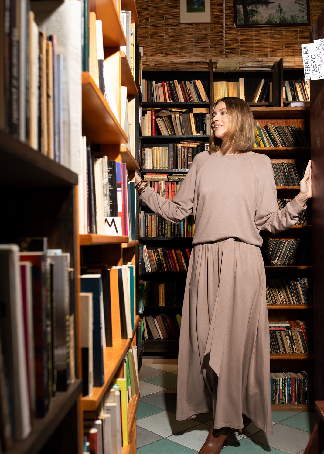 Kobieta w beżowej sukience i swetrze w bibliotece, stylowy strój na co dzień, komfort i elegancja