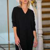 Czarna sukienka z dekoltem w kształcie litery V, idealna na co dzień, z elegancką torebką i biżuterią